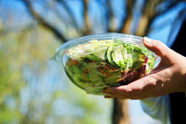eating mixed salad bowl packed in a plastic box outside - junk food stock pictures, royalty-free photos & images