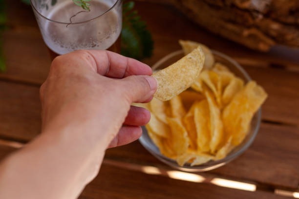 eating potato chips and drinking beer - junk food stock-fotos und bilder