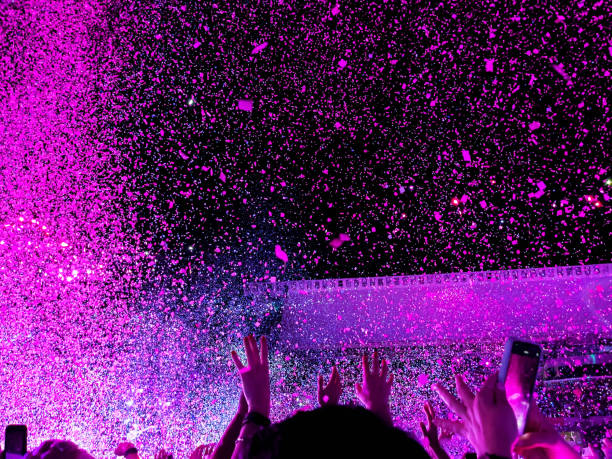 ecstatic people with energy dancing in a vibrant live music concert with pink confetti and crowd with hands up - concert stock pictures, royalty-free photos & images