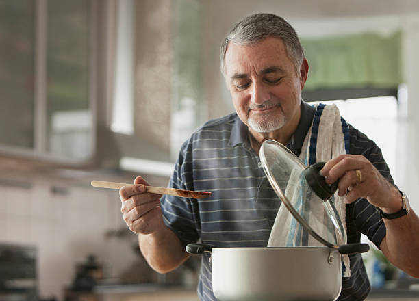 elderly man cooking - food stockfoto's en -beelden