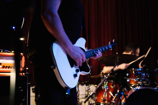 electric guitar player with rock and roll band performing hard rock music on stage - concert stock pictures, royalty-free photos & images