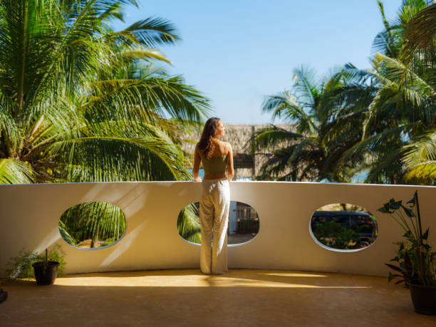 elegant woman on the balcony at sunset looking at palm trees on tourist resort - travel stock pictures, royalty-free photos & images
