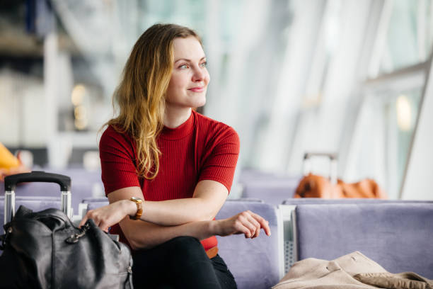 elegant woman smiles while waiting in an airport lounge - travel stock pictures, royalty-free photos & images