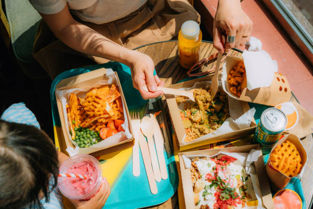 elevated view of young mother and her little girl sharing food at healthy fast-food restaurant - junk food stock pictures, royalty-free photos & images