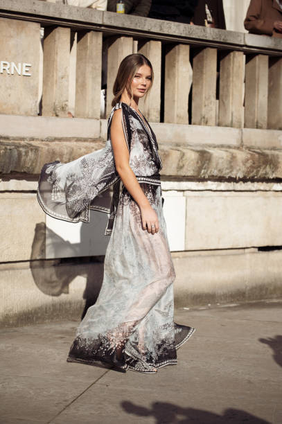 Ellie Thumann wears grey and black pattern sheer dress, sunglasses and black clutch outside the Elie Saab fashion show during the Womenswear...