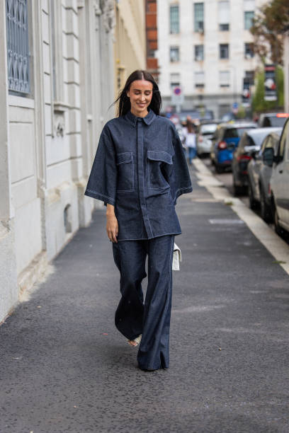Elvira Jain wears oversized dark navy denim button shirt with short sleeves, flared jeans, white bag outside Calcaterra during the Milan Fashion Week...