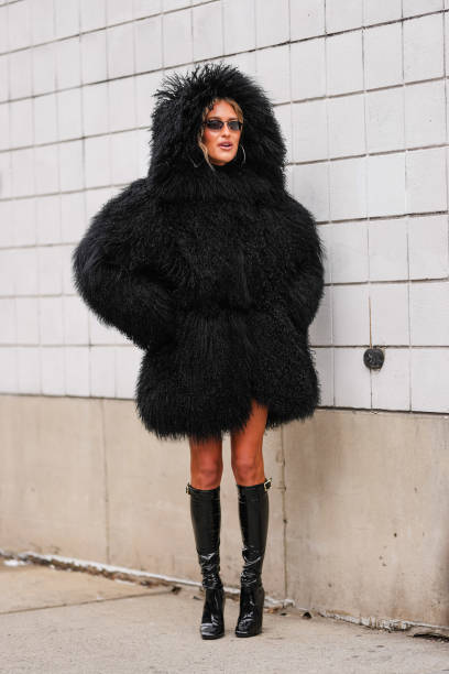 Emili Sindlev wears black faux fur shearling hooded Michael Kors mongolian coat, shiny black knee high heeled boots leather shoes, outside Michael...