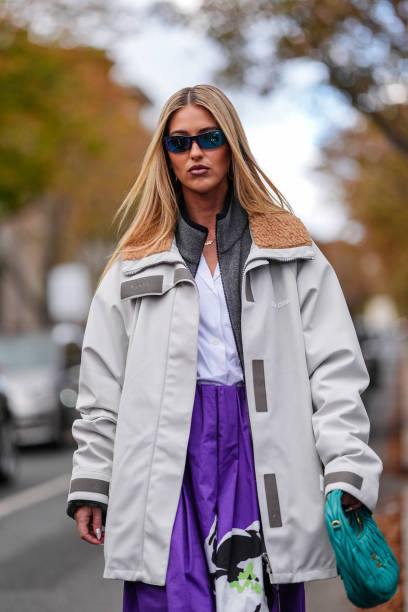 Emili Sindlev wears dark blue sunglasses, dark gray Miu Miu oversized unzipped sweater, white t-shirt, dark purple over the knee graphic white black...