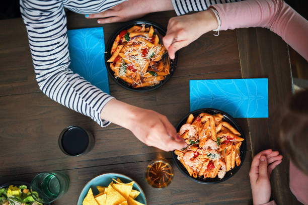 enjoying delivery bowls like pesto cavatappi bowl, meatballs bowl, pasta fresca bowl and grilled chicken caesar salad bowl - junk food stock pictures, royalty-free photos & images