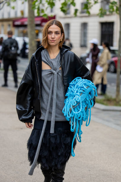 Erika Boldrin wears grey cut out top, blue bag, leather jacket outside Stella McCartney during Womenswear Spring/Summer 2025 as part of Paris Fashion...