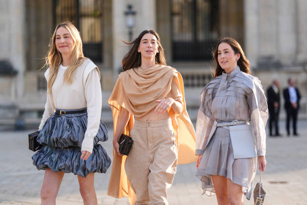 Este Haim wears white long sleeve Louis Vuitton shirt, black leather Louis Vuitton belt, dark blue puffy layered Louis Vuitton mini skirt. Danielle...