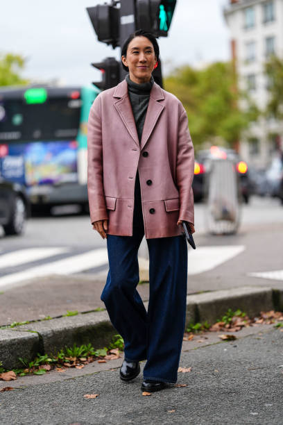 Eva Chen wears dark gray sweater, dark pink oversized blazer jacket, navy blue denim jean pants, shiny black leather boots, outside Chloe, during the...