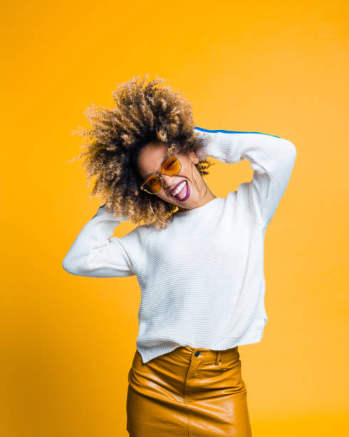 excited afro young woman dancing against yellow background - fashion stock pictures, royalty-free photos & images