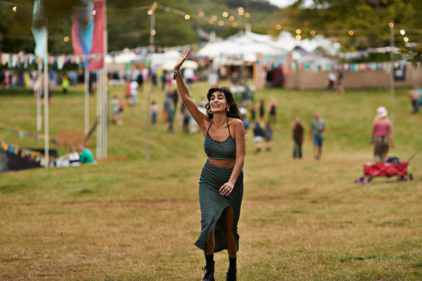 excited woman with raised hand walking at park - concert stock pictures, royalty-free photos & images