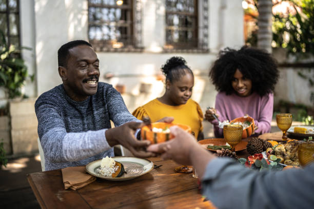 famille mangeant le déjeuner de thanksgiving à la maison - y compris les femmes ayant des besoins spéciaux - garden decoration photos et images de collection