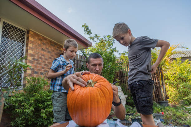 family carving a halloween pumpkin - garden decoration stock-fotos und bilder