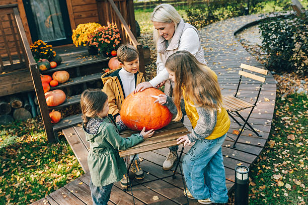 family choosing a big pumpkin for halloween decoration on a wooden porch - garden decoration stock pictures, royalty-free photos & images