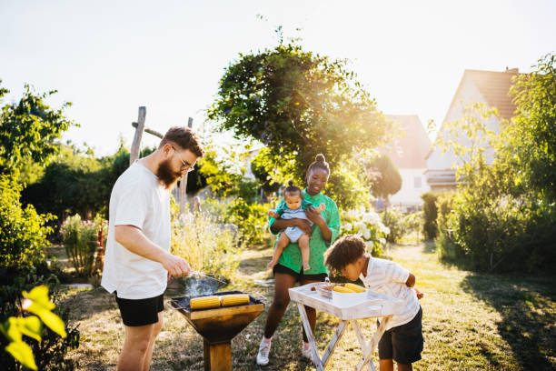 family cooking food on bbq in back garden - garden decoration photos et images de collection