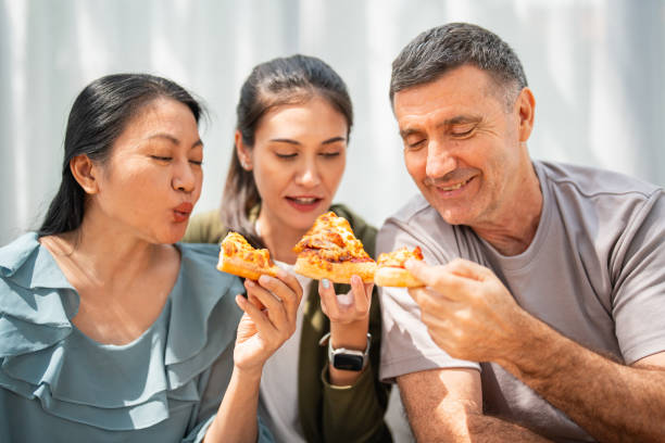 family dining at home on pizza during lunch - junk food stock pictures, royalty-free photos & images