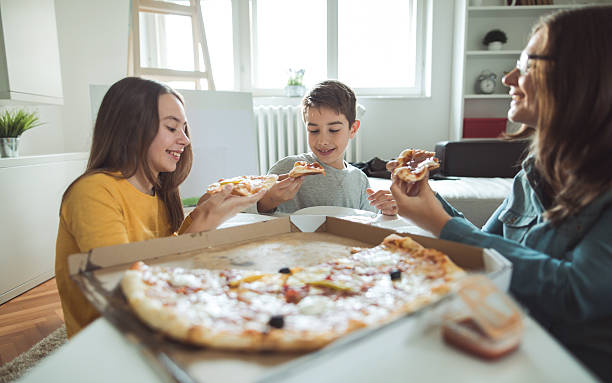 family eating pizza at home - junk food stock pictures, royalty-free photos & images