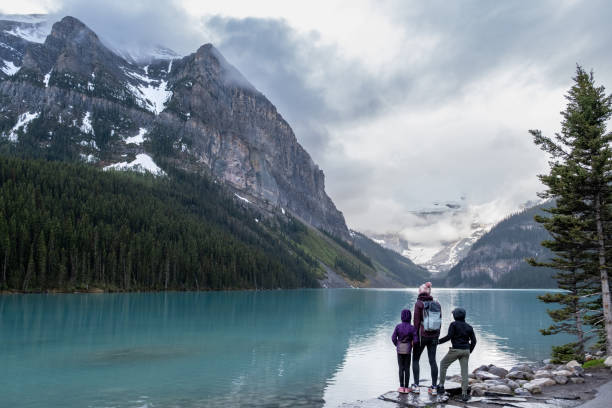 family hiking around a pristine glacial lake in banff national park - travel stock pictures, royalty-free photos & images