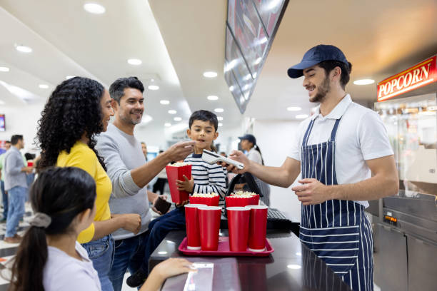 family making a contactless payment while buying snacks at the cinema - junk food stock pictures, royalty-free photos & images