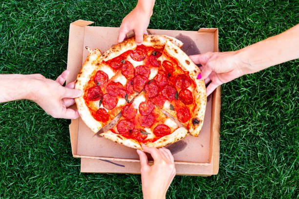 family of four sharing pizza, directly above view - junk food stock pictures, royalty-free photos & images
