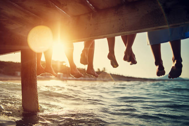 family sitting on pier by the sea - travel stock pictures, royalty-free photos & images