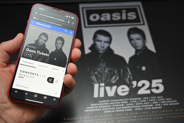 Fan uses a smart phone to access an on-line ticket sales website to purchase tickets for Oasis' "Live '25" tour taking place in 2025, at home in...