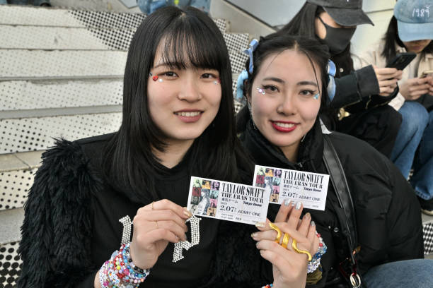 Fans of US singer Taylor Swift, also known as Swifties, pose with their tickets as people gather in front of the Tokyo Dome a few hours ahead of the...