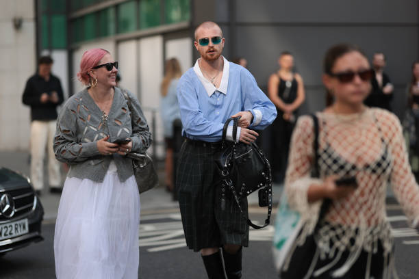 Fashion Show Guest was seen wearing black leather boots, oversized black and white checked shorts with a black belt, green shades, a black bag with...