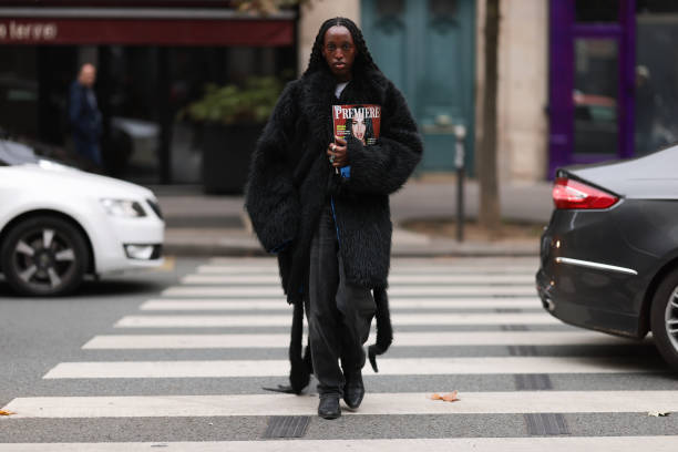 Fashion week guest is seen wearing a long black fur coat with an oversized look, with black baggy jeans and black boots during the Akris Show...