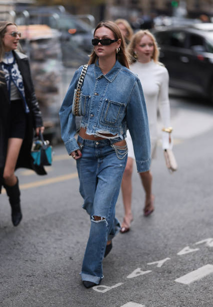 Fashion Week guest is seen wearing rectangular black sunglasses with wide temples; two gold hoop earrings; a matching two-piece consisting of a...