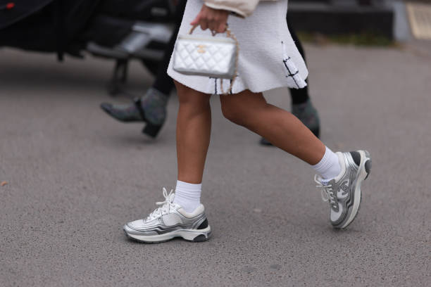 Fashion week guest seen wearing a white dress, a silver bag, white socks and silver and white sneakers before the Chanel show on March 07, 2023 in...