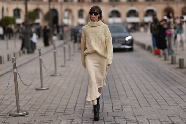 Fashion Week Guest was seen wearing black heels, a beige longsleeve with turtle-neck as well as a matching light beige skirt and dark shades before...