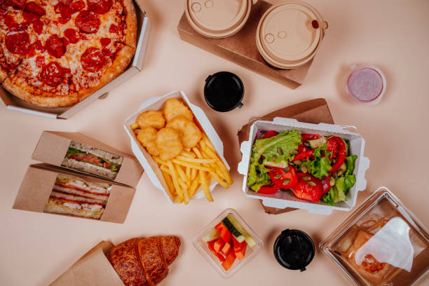 fast foods and vegetable salad near coffee cups against beige background - junk food stock pictures, royalty-free photos & images