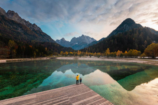 father and son enjoying the view of alpine lake - travel stock-fotos und bilder