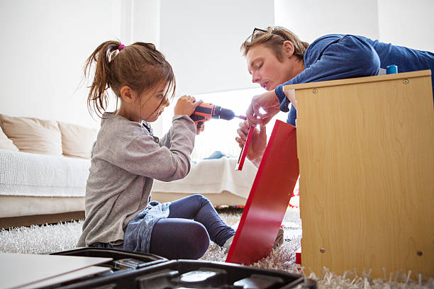 father helping daughter in making toy kitchen - home decoration stock pictures, royalty-free photos & images