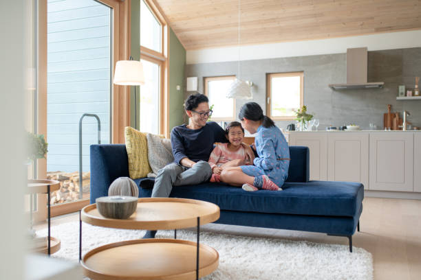 father relaxing with his daughters on the sofa - home decoration stock pictures, royalty-free photos & images