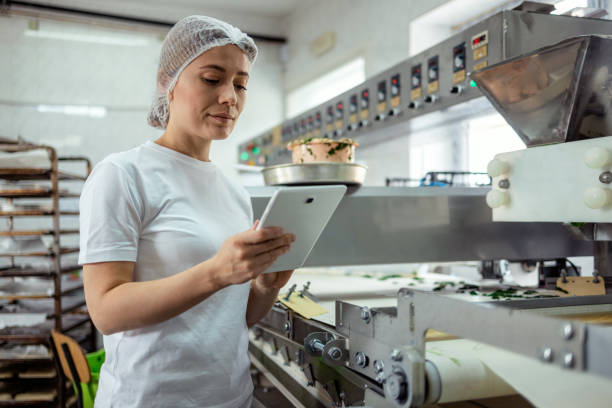 female baker with digital tablet in the bakery - food stockfoto's en -beelden