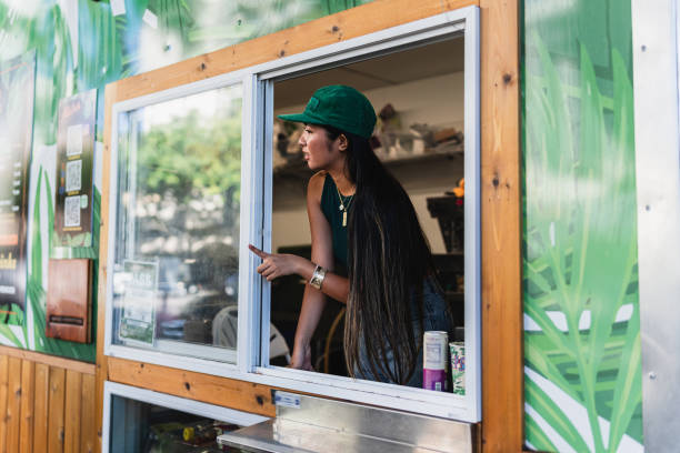female barista looks outside food cart window - junk food stock pictures, royalty-free photos & images