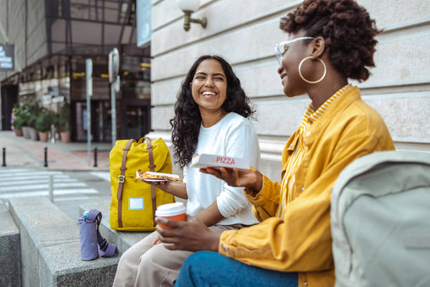 female cheerful tourists have fun eating pizza in the touristic city - junk food stock pictures, royalty-free photos & images