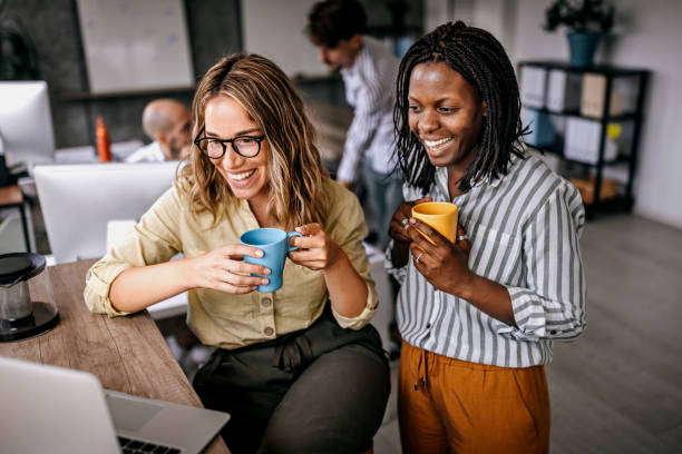 female coworkers looking at laptop and laughing - coffee stock pictures, royalty-free photos & images