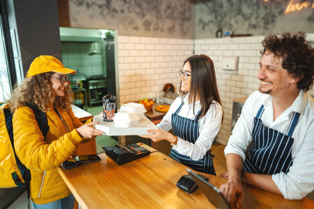 female delivery worker picking up customers order at the bar - junk food stock pictures, royalty-free photos & images