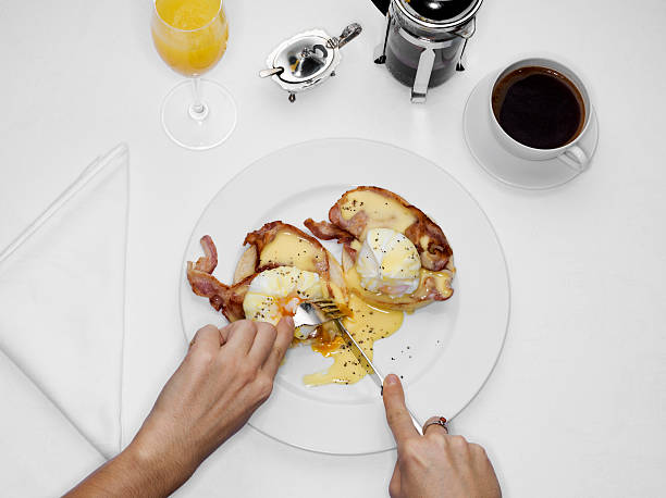 female eating eggs benedict, overhead view - junk food stock pictures, royalty-free photos & images