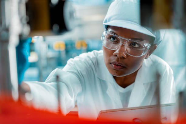 female engineer in a drinking water factory in professional uniform using digital tablet working in beverage industrial. female factory worker use digital tablet testing program in production line. - food stock pictures, roya