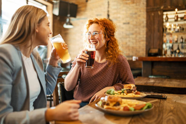 female friends having a beer - junk food stock pictures, royalty-free photos & images
