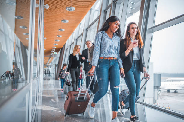 female friends walking by window at airport - travel stock pictures, royalty-free photos & images