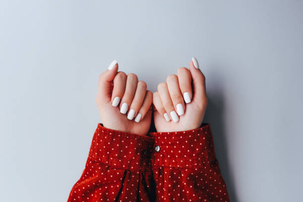female hands with white manicure on a gray background. skin care for hands, cuticles and manicure. beautiful nails. spa for hands. manicurist. - nails art stock pictures, royalty-free photos & images