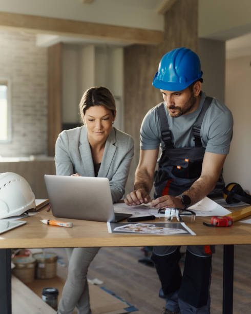female inspector and manual worker using laptop at renovating house. - home decoration stock pictures, royalty-free photos & images